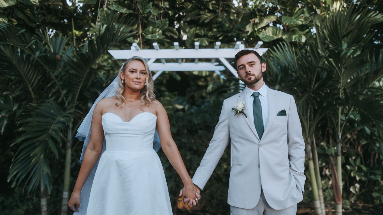 The Art of Drawing Readers In: Your attractive post title goes here A bride and groom holding hands under a white arch in an outdoor wedding setting.